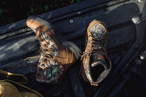 A muted brown leather boot shown in profile view with dirt smudges on the light gray midsole and side of the boot.