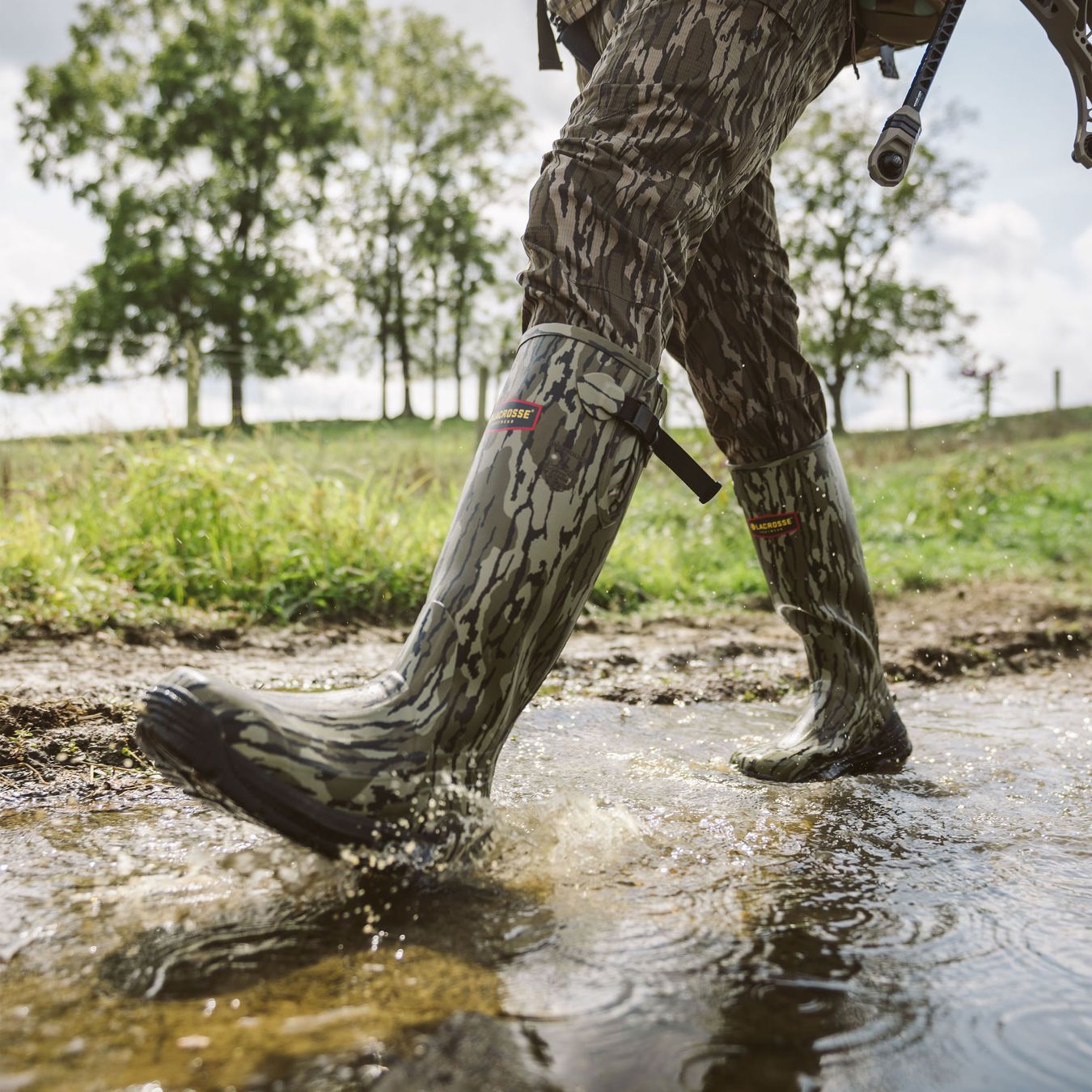 a camo rubber boot cuts through water